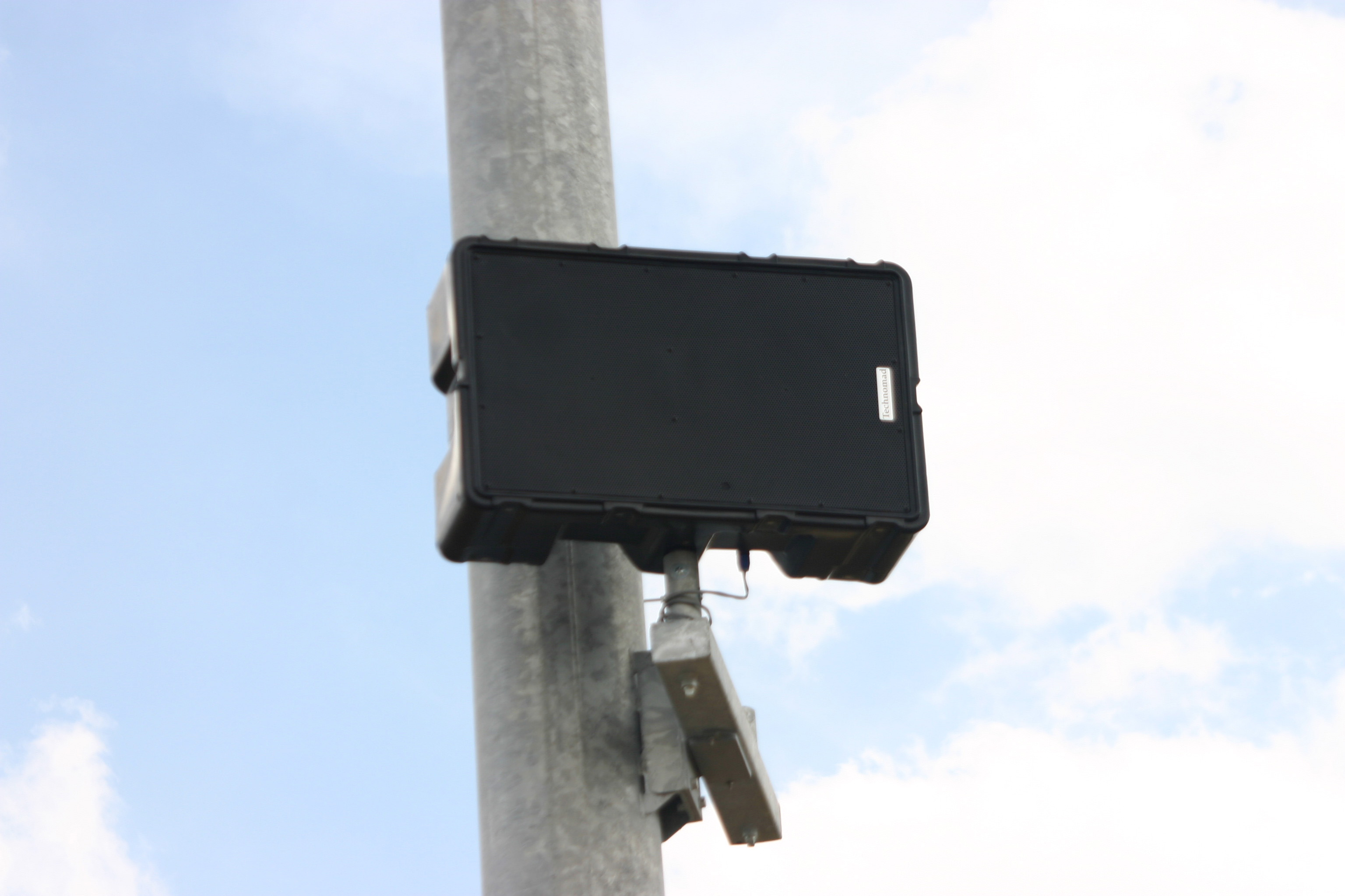 A Technomad Berlin loudspeaker installed on a light pole outdoors and unprotected from the elements